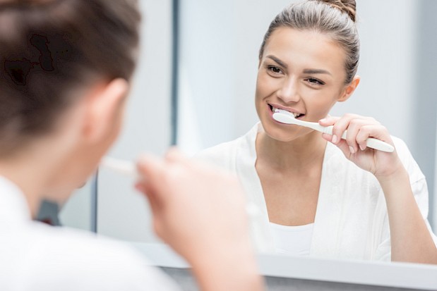 Woman brushing teeth in front of mirror