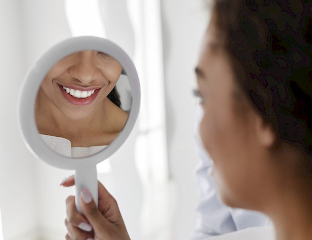 Woman checking teeth in the mirror.